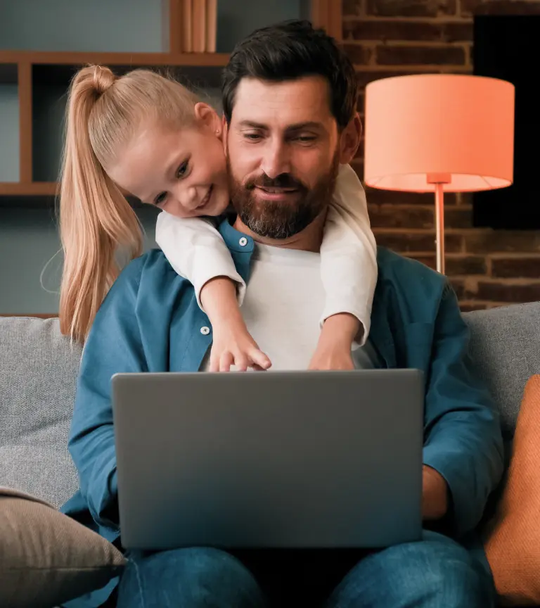 A father and his daughter booking an airport transfer on a laptop at home