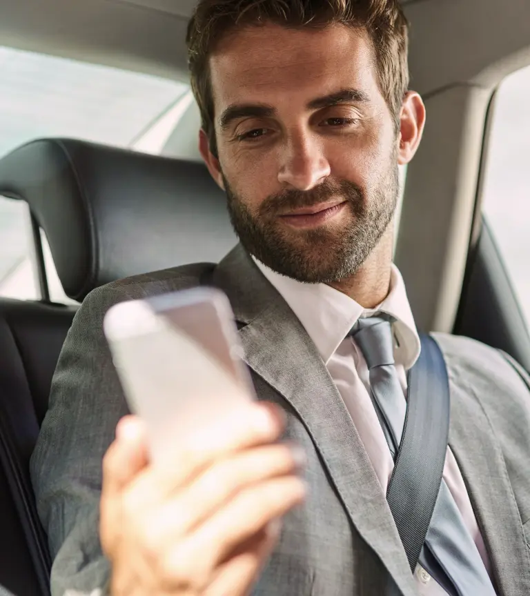 A business traveller relaxing in the back seat of a private car